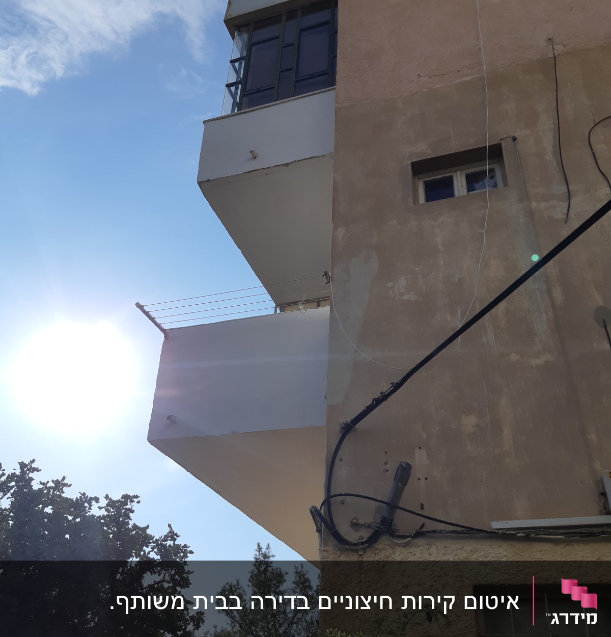 בניין עם מרפסת וחלונות, חוטים חשמליים מחוברים לקיר